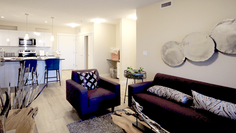 a living room with a couch and chairs and a kitchen in the background